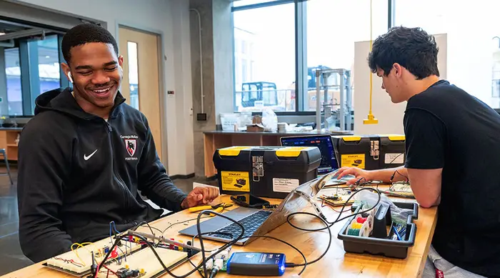 Two Carnegie Mellon students working on circuitry in a lab.