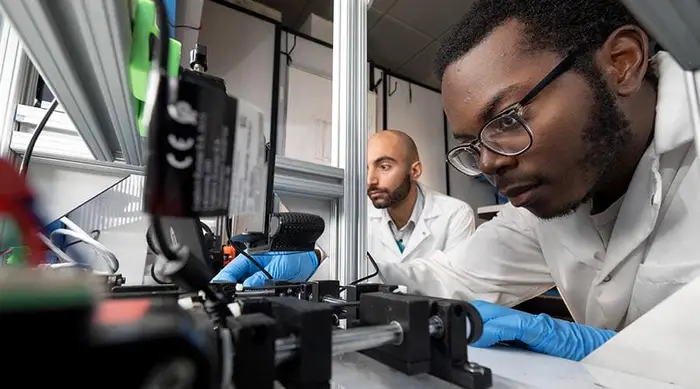 Two Carnegie Mellon students in a laboratory with a microscope.